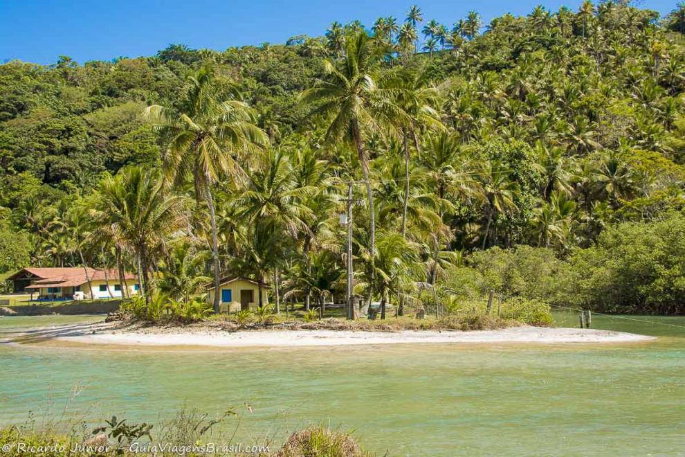 Imagem de uma casa amarela entre coqueiros na Praia Jeribucaçu.